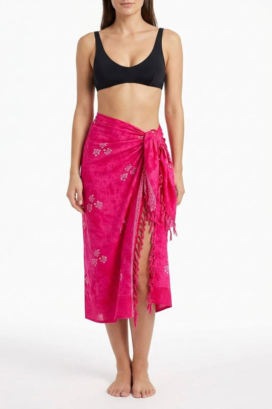 Woman wearing a black bikini top and pink sarong on a white background