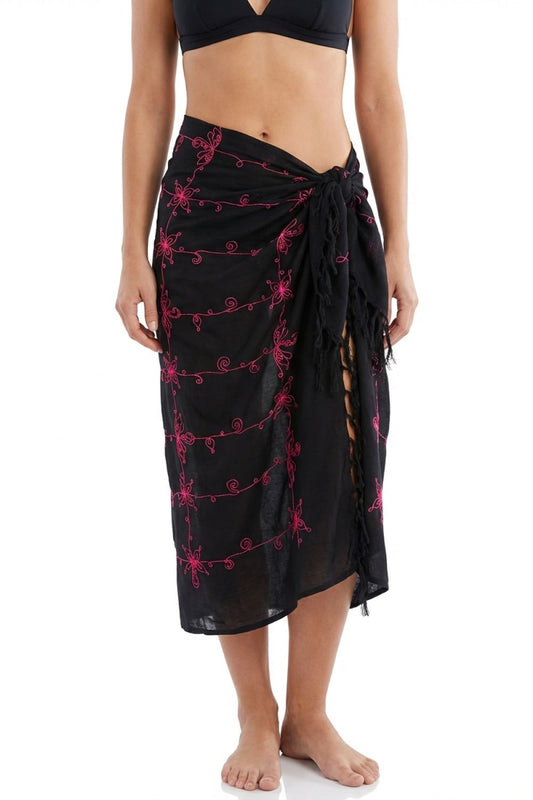 Black sarong with pink floral patterns worn by a person on a white background