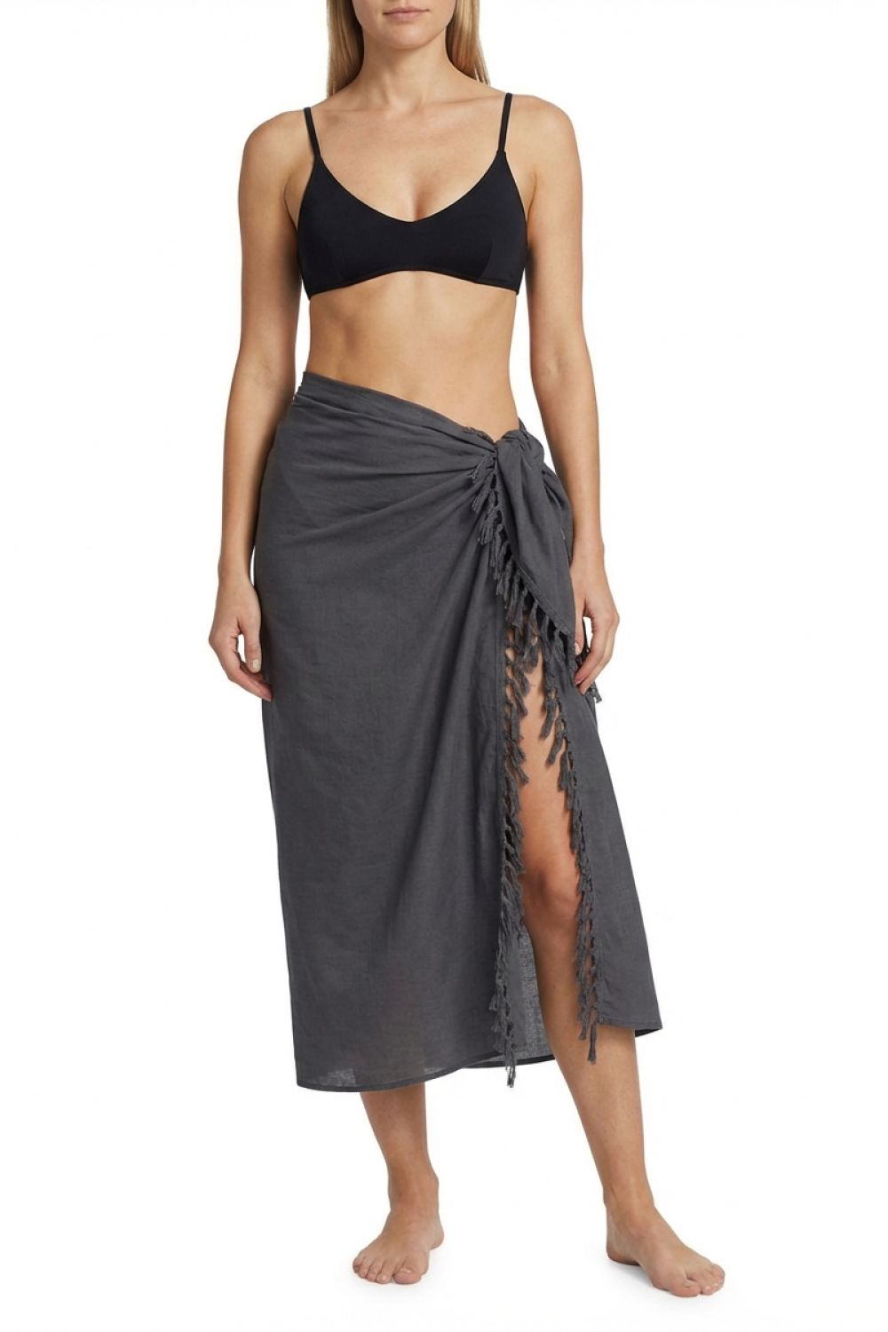 Woman wearing a black bikini top and gray sarong on a white background