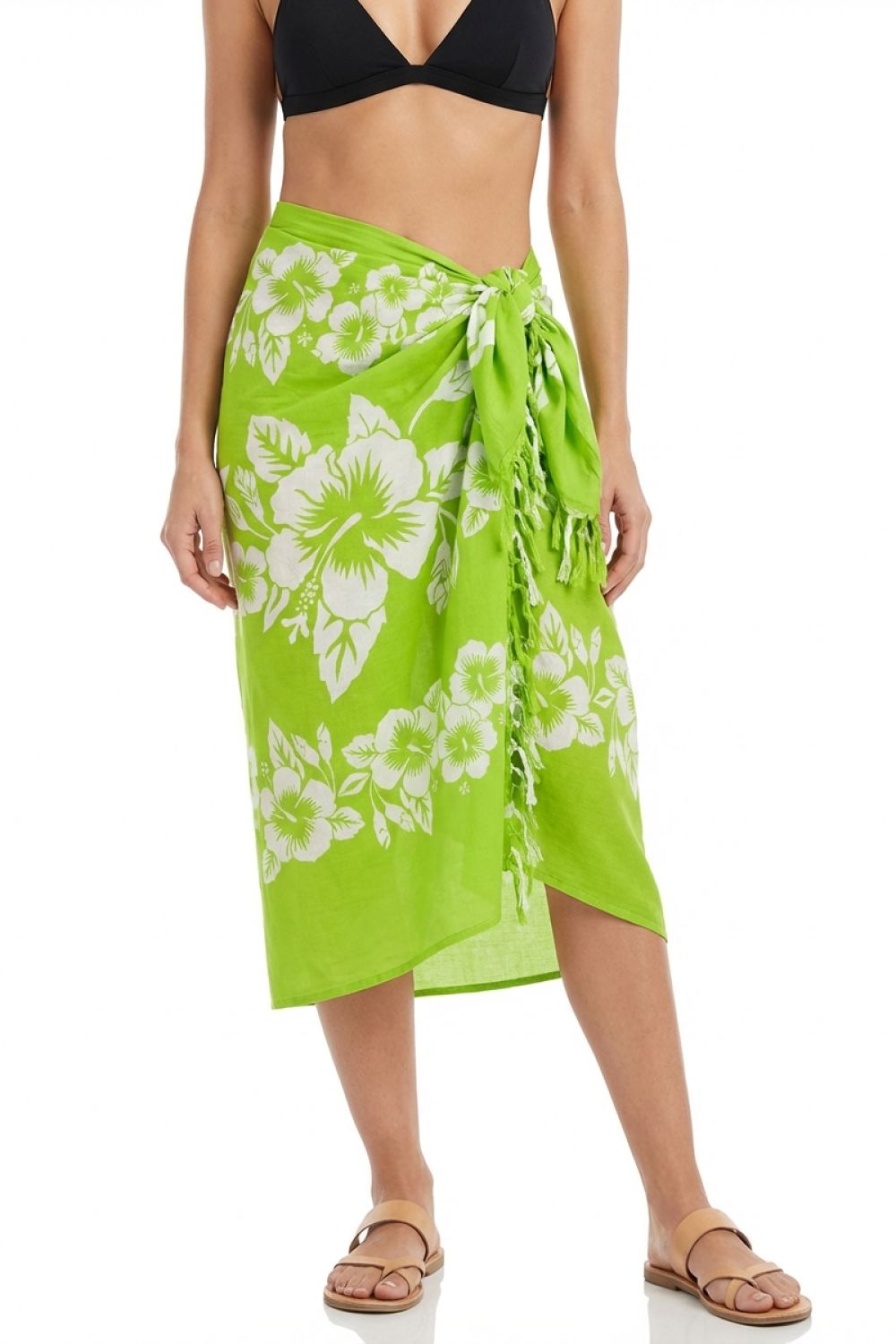 Woman wearing a green floral sarong with a black bikini top on a white background