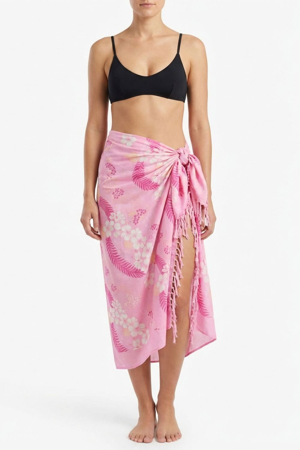 Person wearing a black bikini top and pink floral sarong on a white background
