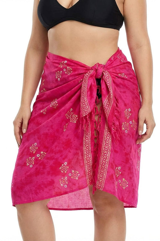 Person wearing a bright pink sarong with turtle patterns on a white background