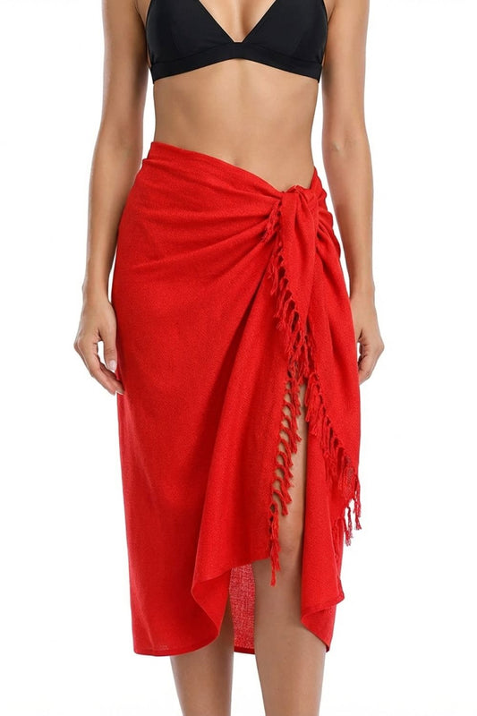 Red sarong with tassels worn over a black bikini top on a white background