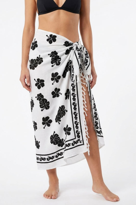 Person wearing a white sarong with black floral patterns on a white background