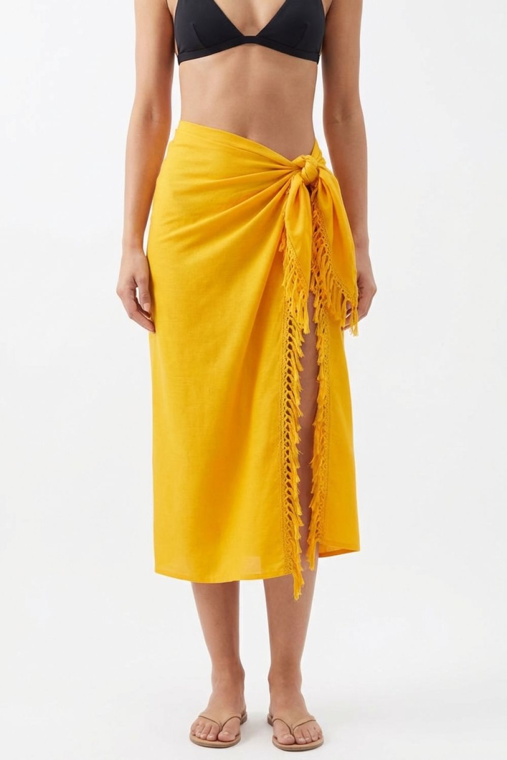 Person wearing a yellow sarong with a black bikini top on a white background