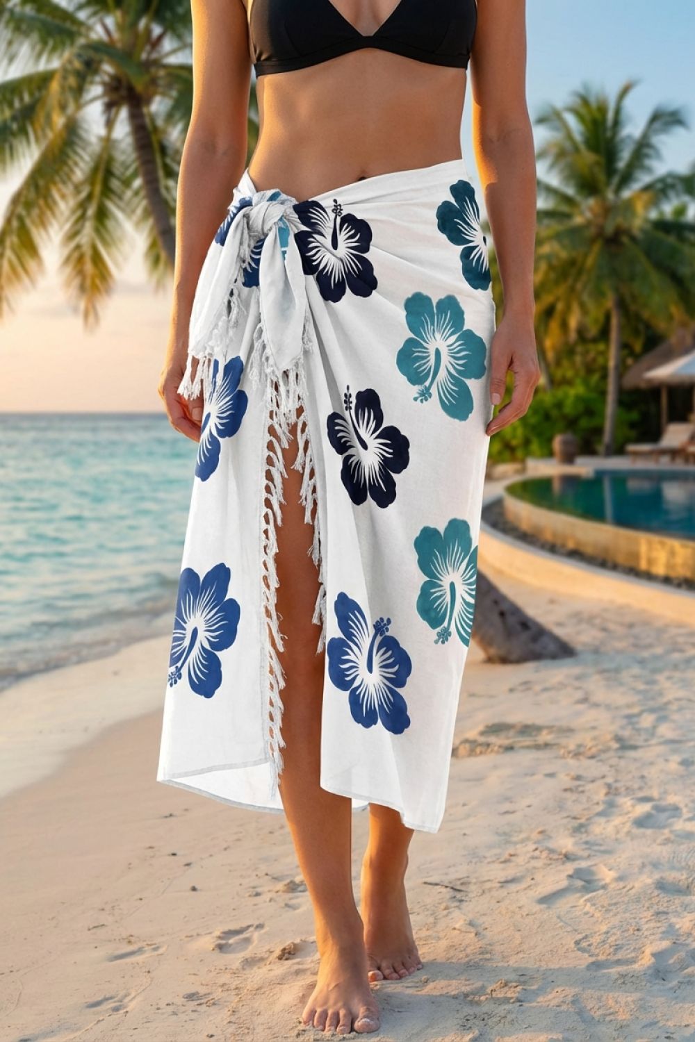 Person wearing a white sarong with blue floral patterns on a beach.